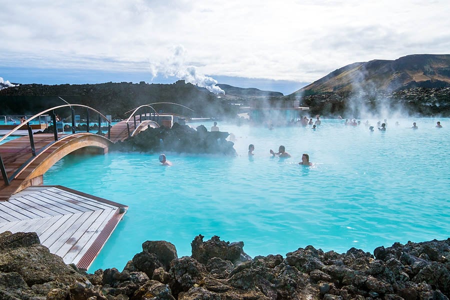 The milky blue, steaming lagoon is surrounded by blackened volcanic pumice stones