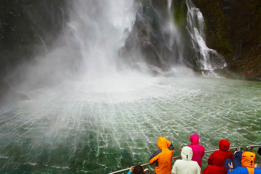 Tourists under the waterfalls of Milford Sound | Travel Nation