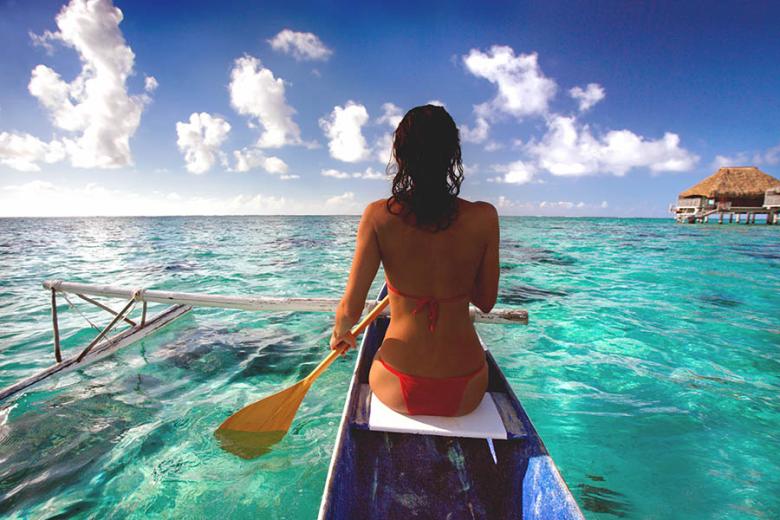 Paddle through turquoise water in outrigger canoe (called a va’a in Tahitian) 