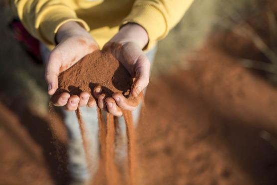 Boy holding red sand in hands | Uluru, Australia