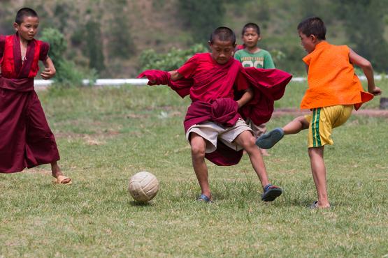 Young Buddhist monks playing football at Chimi Lhakhang temple 
